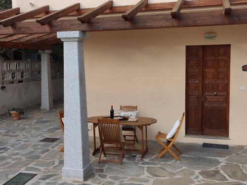 a wooden table and chairs under a wooden pergola at Apartment Stella Maris in Cala Gonone