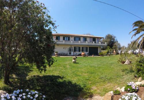 a large house with a yard with flowers at Villa Enli in Capalbio