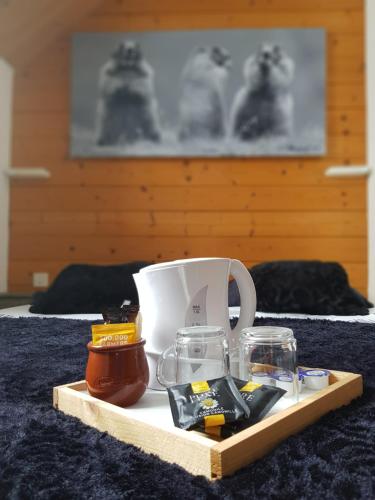 een dienblad met een koffiemok en glazen op een bed bij Gîte Chalet du Soulor in Arrens-Marsous