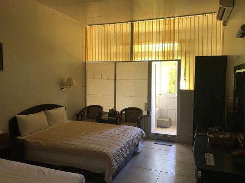 a bedroom with two beds and a sliding glass door at Songboling Hot Spring Inn in Liugui