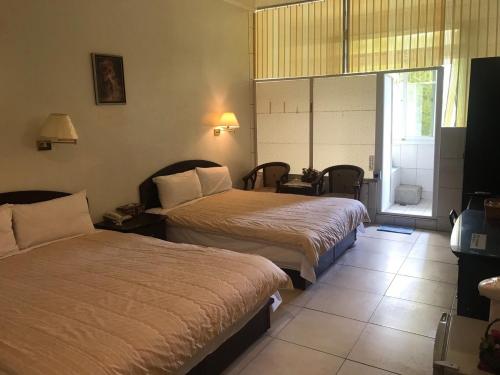 a hotel room with two beds and a window at Songboling Hot Spring Inn in Liugui