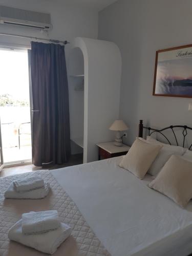 a bedroom with a large white bed with two towels on it at Emmanouela Studios & Villas in Karterados