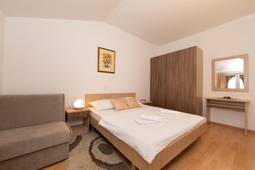 a bedroom with a bed and a couch at Apartments Simovic in Tučepi