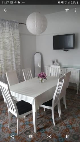 a white dining room table with white chairs and a tv at Barko apartment and rooms in Hvar