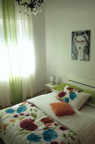 a bedroom with a bed with a flowered blanket and a window at Barko apartment and rooms in Hvar