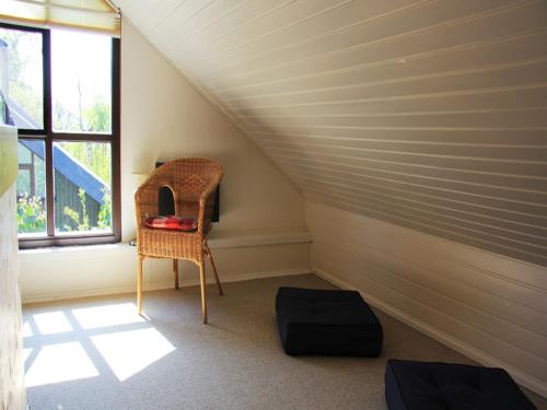 a attic room with a chair and a window at Gut Karlsminde in Waabs