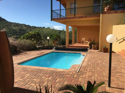 a swimming pool in front of a house at Felsenblick Self-Catering in Windhoek