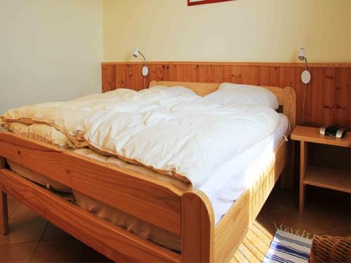 a large wooden bed with white sheets on it at Gut Karlsminde in Waabs