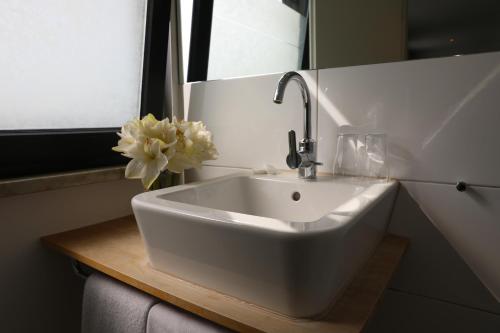 - un lavabo blanc dans la salle de bains pourvue d'un vase de fleurs dans l'établissement Hotel Weinlaube, à Coblence