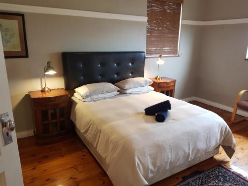 Schlafzimmer mit einem großen Bett mit einem schwarzen Kopfteil in der Unterkunft Bramber Court Art-Deco Self-Catering Apartments in Kapstadt