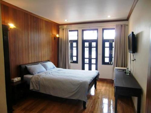 a bedroom with a bed and a flat screen tv at The Royal ThaTien Village in Bangkok