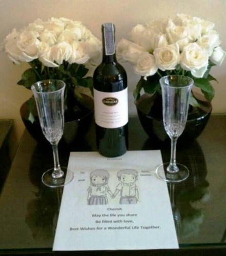 a bottle of wine and two glasses on a table with flowers at The Royal ThaTien Village in Bangkok