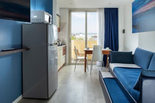 a kitchen and a living room with a refrigerator and a table at Residence Queen in Rimini