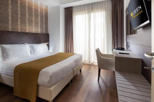 a hotel room with a bed and a desk and a television at Residence Queen in Rimini