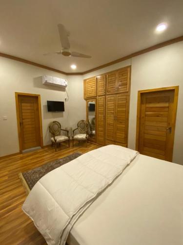 a bedroom with a white bed and wooden floors at ISLE OF HIGHLAND TOURS Guest House in Gilgit
