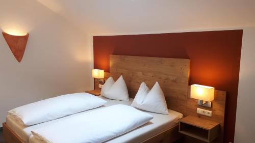 a bedroom with two beds with white pillows and lights at Pension Irlingerhof in Mondsee