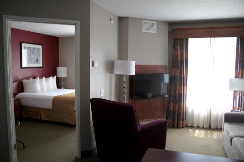 a hotel room with a bed and a chair and a television at GrandStay Hotel & Suites Ames in Ames