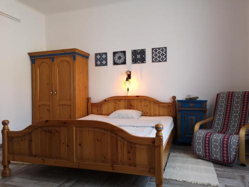 a bedroom with a wooden bed and a chair at Gyöngyszem Vendégház in Eger