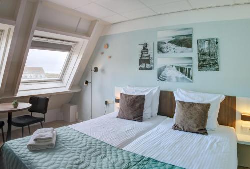 a bedroom with a bed and a window and a table at Hotel Duinlust in Domburg