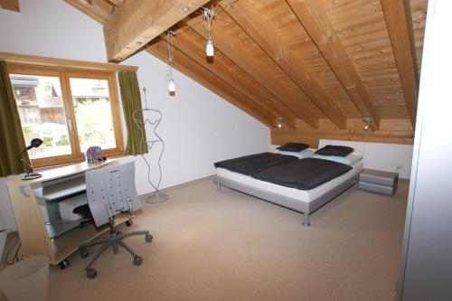 Schlafzimmer mit einem Bett, einem Schreibtisch und einem Fenster in der Unterkunft Gotschnablick in Klosters