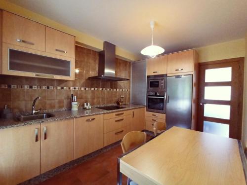 ア・コルーニャにあるCasa Mar de Ardoraのキッチン(木製キャビネット、ステンレス製の冷蔵庫付)