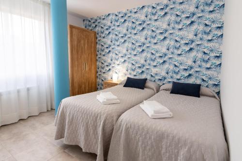 twee bedden in een slaapkamer met blauw en wit behang bij JAIME I in Valderrobres
