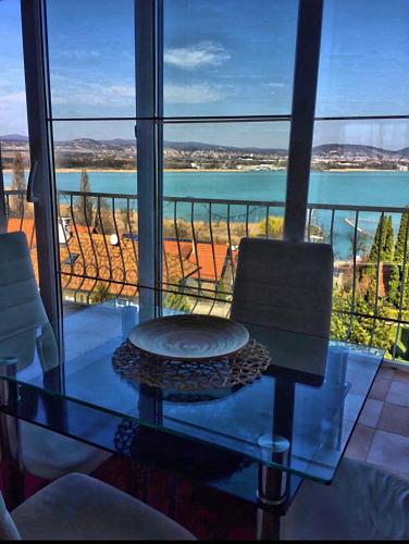a glass table with two chairs and a view of the ocean at Villa Borostyán in Tihany