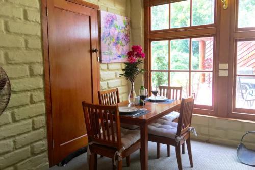 a dining room with a table and chairs and windows at BEAUTIFUL RETREAT - 20 mins to CBD and only 10 mins to MONA! in Collinsvale