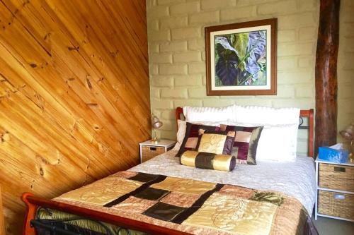 a bedroom with a bed with a wooden wall at BEAUTIFUL RETREAT - 20 mins to CBD and only 10 mins to MONA! in Collinsvale