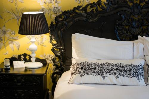 a bed with a black and white pillow and a lamp at Beachlands Hotel in Weston-super-Mare