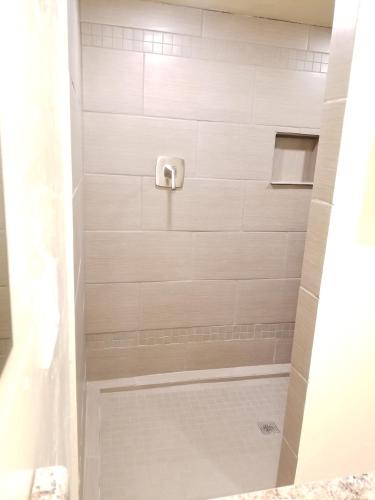 a bathroom with a shower with white tile at Tucson Airport Oasis in Tucson