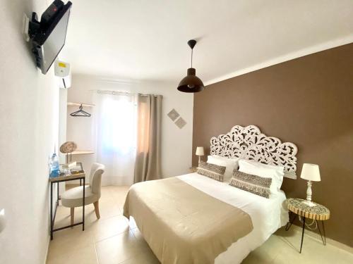 sypialnia z dużym białym łóżkiem i telewizorem w obiekcie Pátio Abílio Guest House w mieście Nazaré