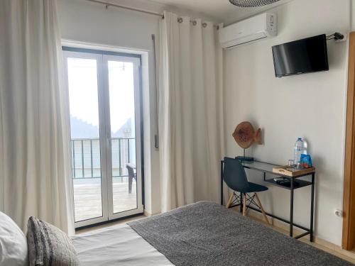 ナザレにあるPátio Abílio Guest Houseのベッドと机と窓のある寝室