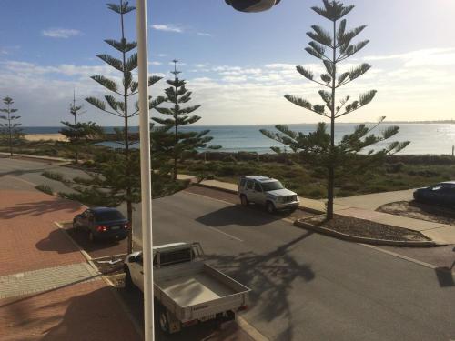 a street with cars parked in a parking lot near the ocean at Breakwater Short Stay in Mandurah