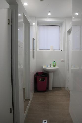 a white bathroom with a sink and a window at Backpackers Imperial Hotel in Hobart