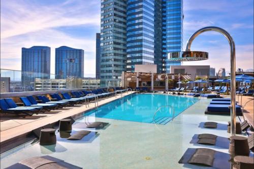 a pool on the roof of a building with chairs and buildings at Stay Together Suites - Condominium On The Strip Sleeps 16 - NO RESORT FEE in Las Vegas