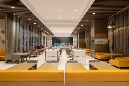 a dining room with tables and yellow chairs at Holiday Inn Express Beijing Yizhuang by IHG - Taxi 1 Hour to International Airport and 800 Meters to the Nearby Subway in Daxing