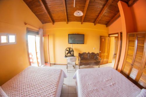 a bedroom with two beds and a tv on the wall at Euro Hostal in Guatemala
