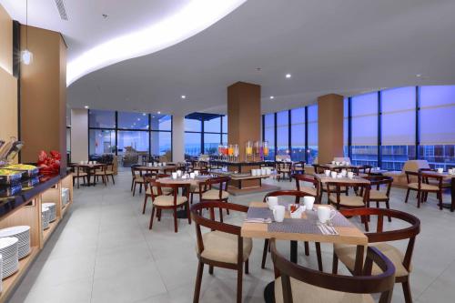 um restaurante com mesas, cadeiras e janelas em Quest Prime Cikarang by ASTON em Bekasi