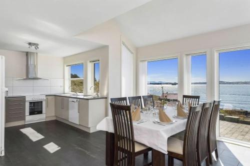 a dining room with a table and chairs and a kitchen at Åmøy Fjordferie in Vestre Amoy