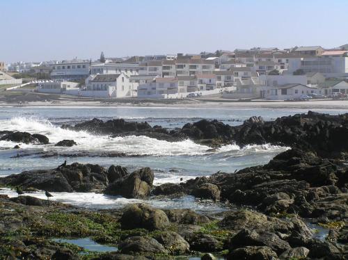 a view of a beach with rocks and buildings at Small Bay Guest House in Bloubergstrand