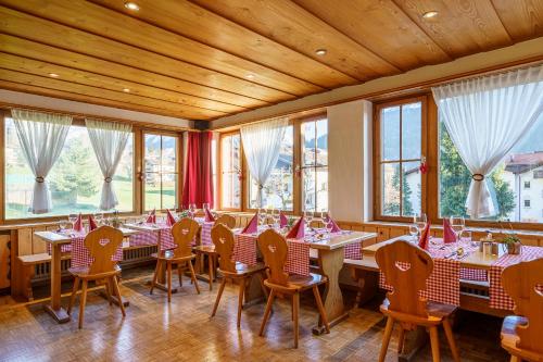 uma sala de jantar com mesas, cadeiras e janelas em Hotel Silvapina em Klosters