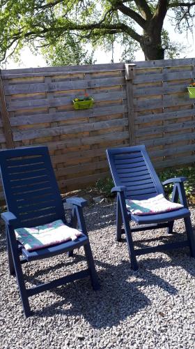 two blue chairs sitting next to a wooden fence at La chambre d Angeline in Foy-Notre-Dame