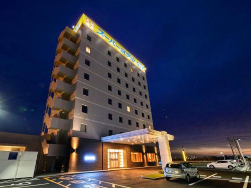 Super Hotel Kashima في Kamisu: فندق فيه سيارات متوقفة في مواقف