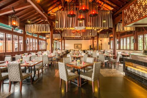 La Floret Villas Yalong Bay Sanya في سانيا: غرفة طعام بها طاولات وكراسي وثريات