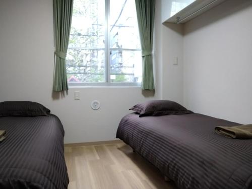 two beds in a bedroom with a window at Issyuku Higashiueno Hotel in Tokyo