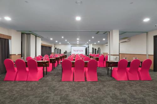 a conference room with pink chairs and tables and a screen at favehotel Malang in Malang