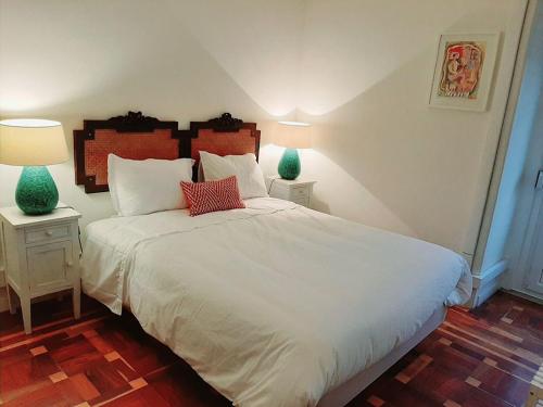 Magnolia Guesthouse في لشبونة: غرفة نوم بسرير ابيض كبير مع مواقف ليلتين