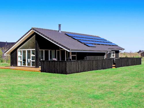a black house with solar panels on the roof at 8 person holiday home in Brovst in Brovst