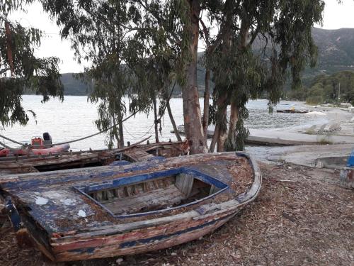 an old boat sitting on the shore of a lake at Ionian Trilogy Luxury Villas in Sami